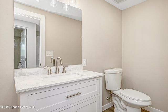 half bathroom featuring baseboards, toilet, and vanity