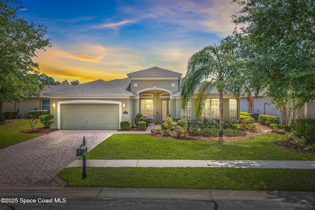 366 Gardendale Cir SE, Palm Bay, FL 32909 - mediterranean / spanish house featuring roof with shingles, stucco siding, an attached garage, a lawn, and decorative driveway