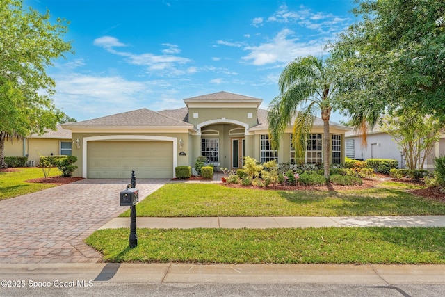 366 Gardendale Cir SE, Palm Bay, FL 32909 - mediterranean / spanish-style home featuring decorative driveway, a garage, a front yard, roof with shingles, and stucco siding