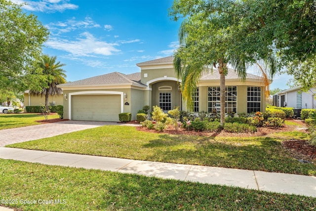 366 Gardendale Cir SE, Palm Bay, FL 32909 - view of front facade featuring stucco siding, a front lawn, a shingled roof, decorative driveway, and a garage