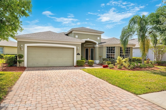 366 Gardendale Cir SE, Palm Bay, FL 32909 - view of front of home featuring stucco siding, decorative driveway, a front yard, a garage, and a shingled roof