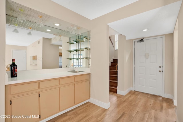 bar with baseboards, light wood-style flooring, a sink, stairs, and bar
