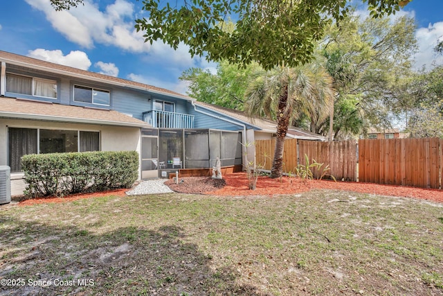 back of property featuring central AC unit, fence, a yard, a sunroom, and a shingled roof