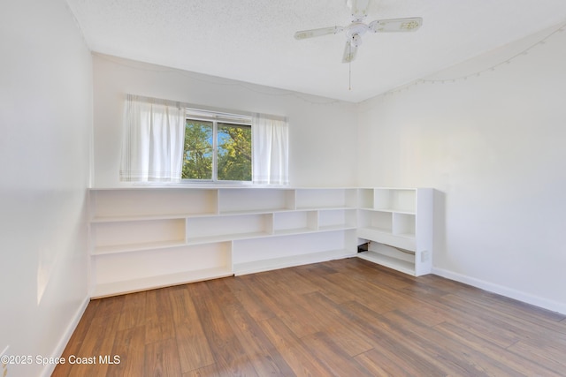 unfurnished room with a textured ceiling, a ceiling fan, baseboards, and wood finished floors