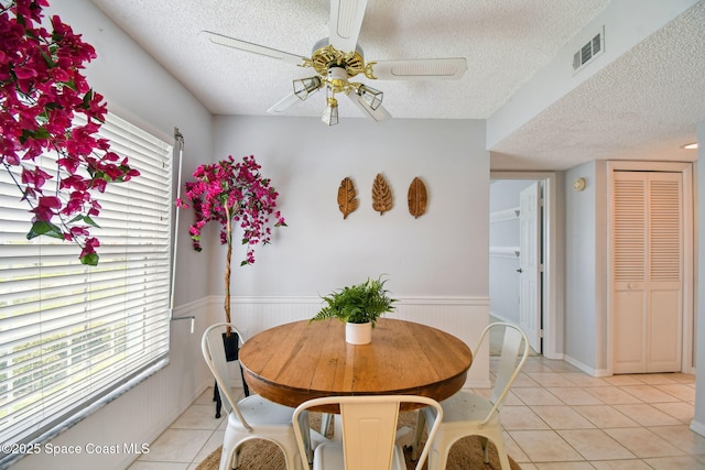 540 S Brevard Ave Unit 427, Cocoa Beach, FL 32931 - dining space featuring a textured ceiling, a ceiling fan, light tile patterned floors, and a wainscoted wall