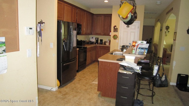 112 Broyles Dr SE, Palm Bay, FL 32909 - kitchen featuring baseboards, arched walkways, light countertops, and black appliances