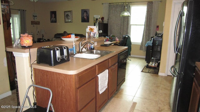 112 Broyles Dr SE, Palm Bay, FL 32909 - kitchen featuring light tile patterned flooring, black appliances, a center island with sink, brown cabinetry, and a sink