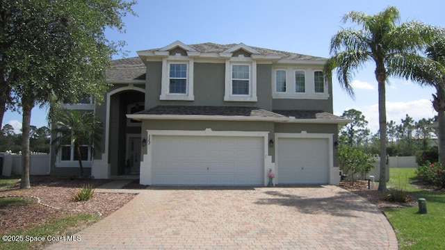 112 Broyles Dr SE, Palm Bay, FL 32909 - view of front of house with an attached garage, stucco siding, fence, and decorative driveway