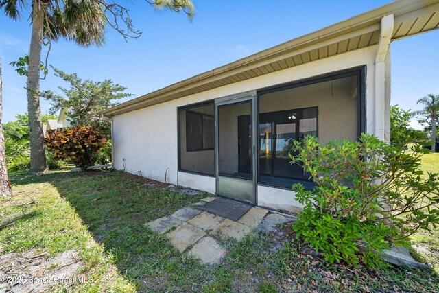 1730 Bluebird Ct, Melbourne, FL 32935 - rear view of property with a yard, stucco siding, and a sunroom