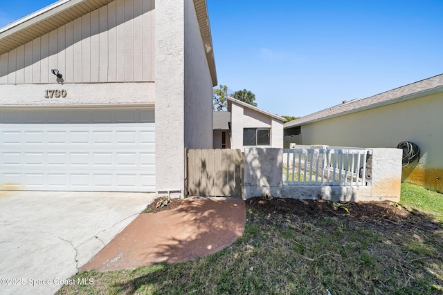 1730 Bluebird Ct, Melbourne, FL 32935 - view of home's exterior with a garage, fence, concrete driveway, stucco siding, and a gate
