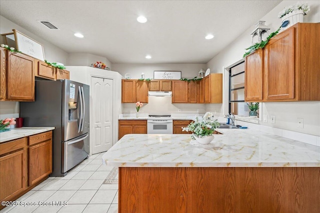 kitchen featuring electric range, light countertops, stainless steel refrigerator with ice dispenser, and visible vents