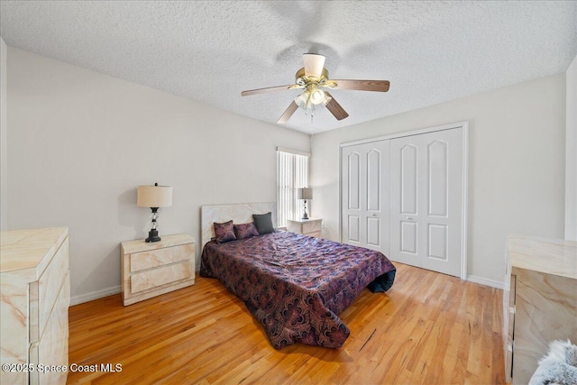 bedroom featuring a closet, baseboards, a textured ceiling, and wood finished floors