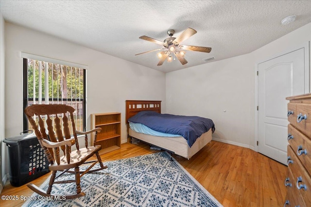 bedroom with baseboards, visible vents, wood finished floors, and a textured ceiling
