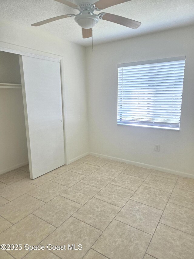120 San Juan Cir, Melbourne, FL 32935 - unfurnished bedroom with baseboards, light tile patterned flooring, ceiling fan, a closet, and a textured ceiling