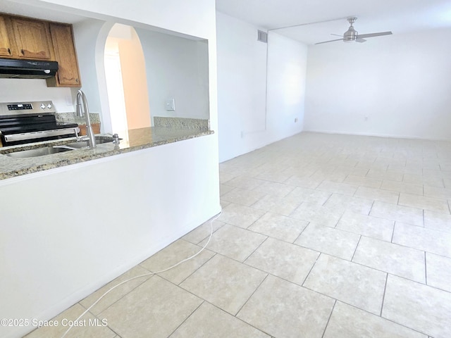 120 San Juan Cir, Melbourne, FL 32935 - kitchen with under cabinet range hood, stainless steel electric stove, arched walkways, brown cabinetry, and ceiling fan