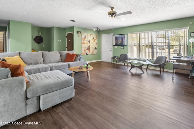 living room featuring dark wood-style floors, baseboards, a textured ceiling, and ceiling fan