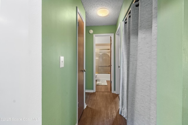 hall featuring baseboards, dark wood-style flooring, and a textured ceiling