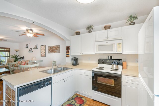 785 Luminary Cir Unit 103, Melbourne, FL 32901 - kitchen with white appliances, a sink, a peninsula, light wood finished floors, and white cabinets