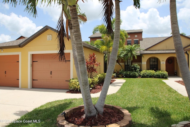 785 Luminary Cir Unit 103, Melbourne, FL 32901 - view of front of home featuring stucco siding, a front yard, concrete driveway, a shingled roof, and an attached garage