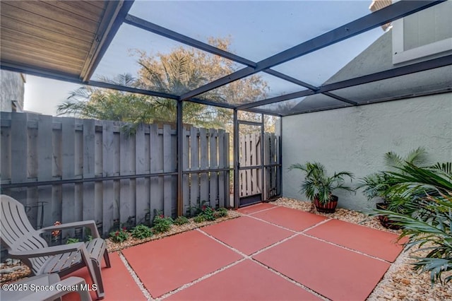 view of patio featuring glass enclosure and fence