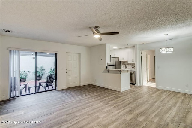 unfurnished living room with baseboards, light wood-style floors, visible vents, and ceiling fan