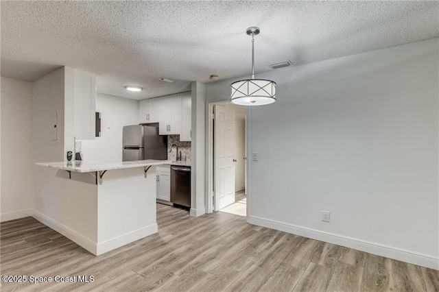 kitchen featuring a breakfast bar, visible vents, stainless steel appliances, and light wood-type flooring