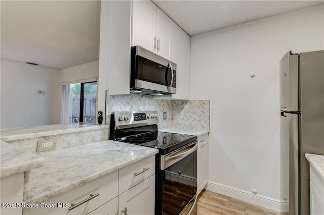 kitchen with tasteful backsplash, white cabinetry, stainless steel appliances, and light wood-style floors