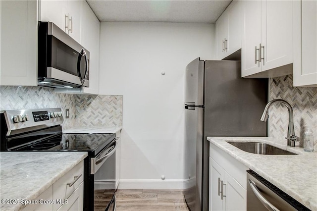 kitchen featuring a sink, stainless steel appliances, white cabinets, and light countertops