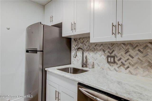 kitchen with a sink, backsplash, white cabinetry, stainless steel appliances, and light countertops