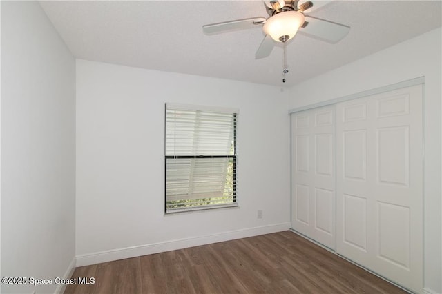 unfurnished bedroom featuring ceiling fan, a closet, baseboards, and wood finished floors