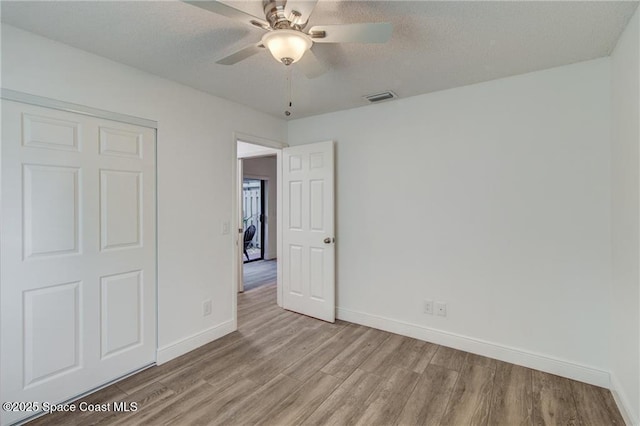 unfurnished bedroom featuring visible vents, ceiling fan, baseboards, wood finished floors, and a textured ceiling