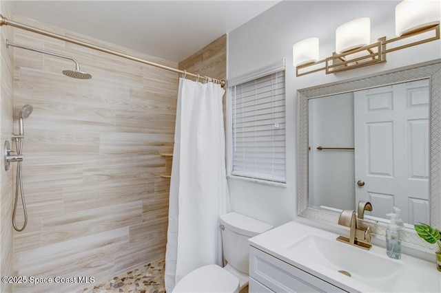 bathroom featuring a tile shower, toilet, and vanity