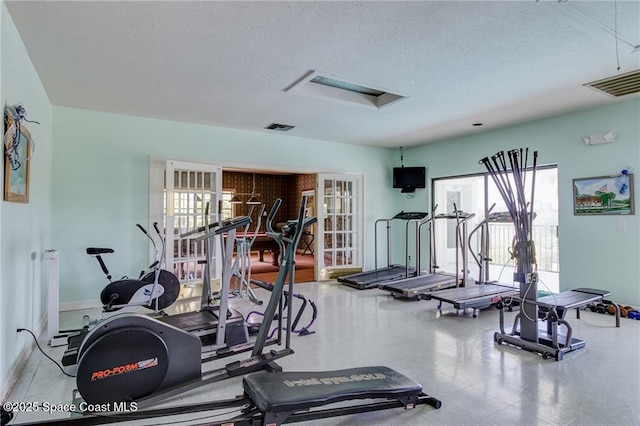 exercise room featuring french doors, a textured ceiling, and visible vents