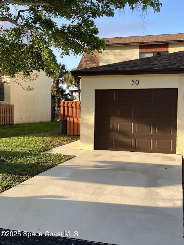 garage with fence and concrete driveway