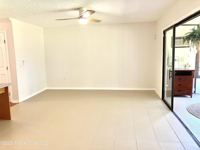 spare room featuring a textured ceiling, a ceiling fan, and baseboards
