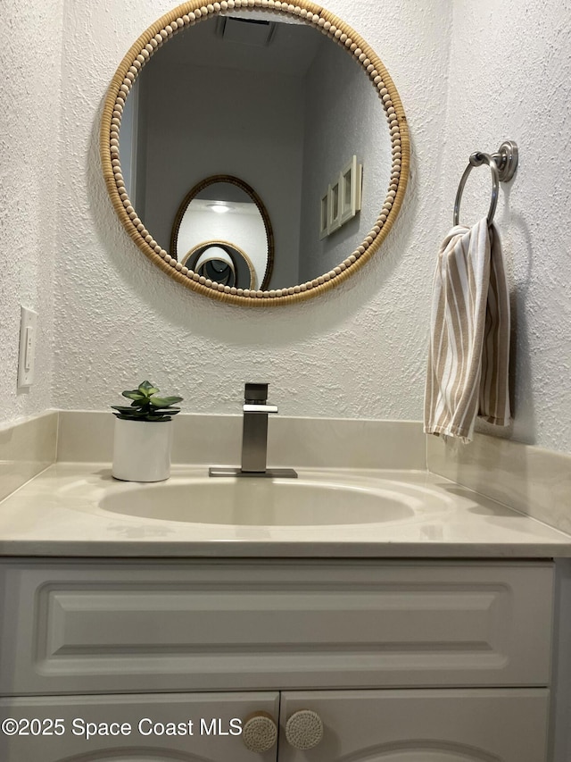 bathroom with a textured wall and vanity