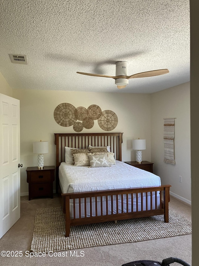 carpeted bedroom featuring baseboards, visible vents, ceiling fan, and a textured ceiling