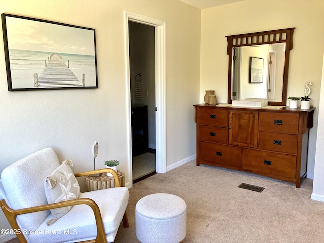 sitting room featuring baseboards, visible vents, and light carpet