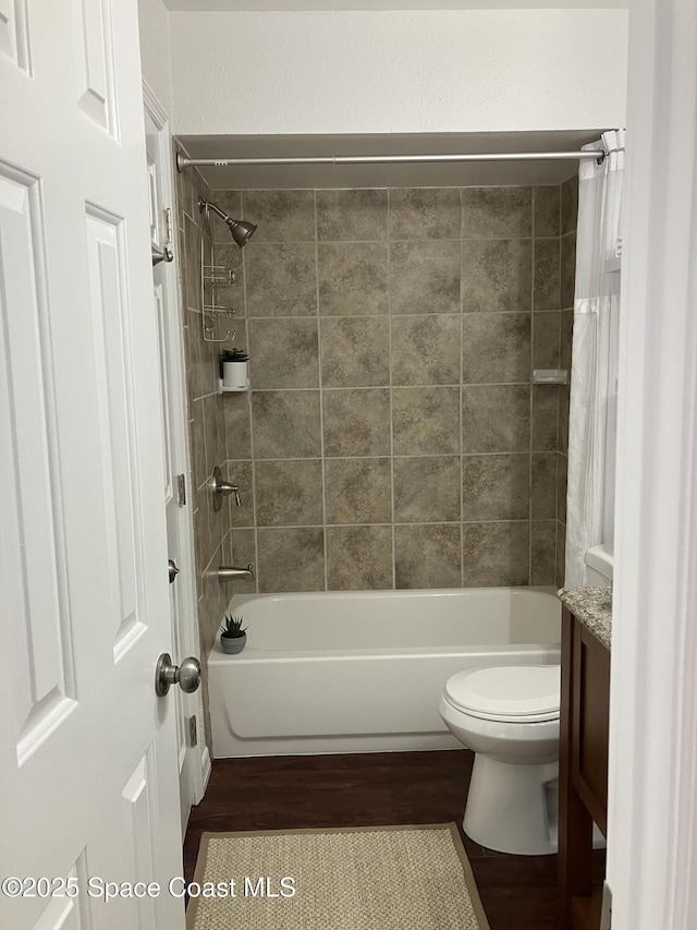 full bath with shower / bath combo, wood finished floors, toilet, and vanity
