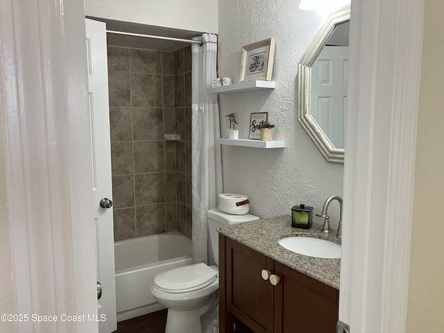 full bath featuring toilet, shower / bath combo, a textured wall, and vanity