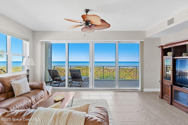 2485 S Atlantic Ave Unit 101, Cocoa Beach, FL 32931 - living room with ceiling fan, a water view, light tile patterned flooring, and a textured ceiling