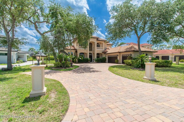 5454 Riveredge Dr, Titusville, FL 32780 - mediterranean / spanish home with decorative driveway, a front lawn, a garage, stucco siding, and a tiled roof