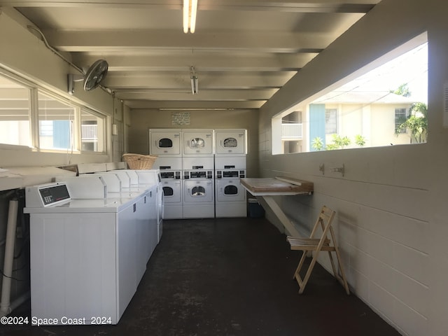 community laundry room featuring washing machine and clothes dryer, a healthy amount of sunlight, and stacked washer / dryer