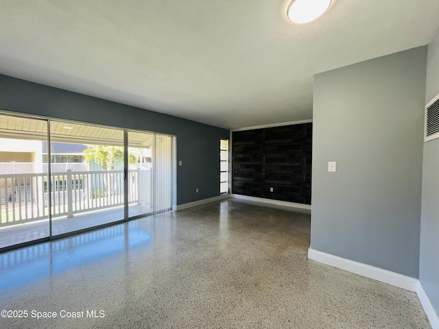 unfurnished living room featuring baseboards and speckled floor