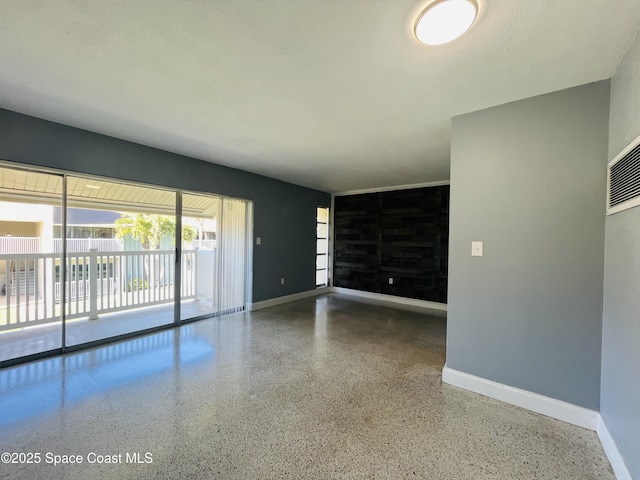 unfurnished living room featuring baseboards and speckled floor