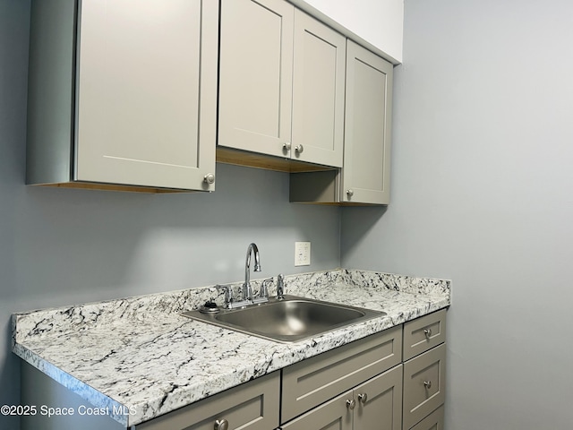 kitchen with gray cabinetry, light countertops, and a sink