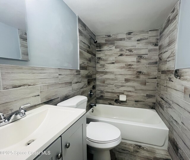 bathroom with toilet, vanity, tile walls, and shower / bathtub combination