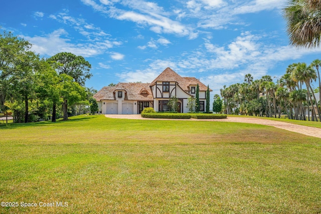 7021 S Tropical Trl, Merritt Island, FL 32952 - english style home featuring curved driveway, stucco siding, a garage, and a front lawn