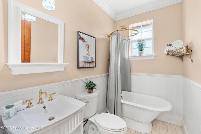 7021 S Tropical Trl, Merritt Island, FL 32952 - bathroom featuring wainscoting, a freestanding bath, toilet, crown molding, and wood finished floors