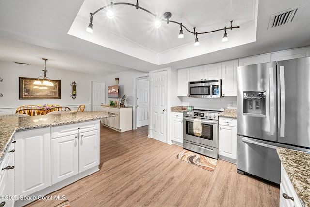 445 Park Ave, Satellite Beach, FL 32937 - kitchen featuring stainless steel appliances, a tray ceiling, track lighting, white cabinets, and light wood-style floors